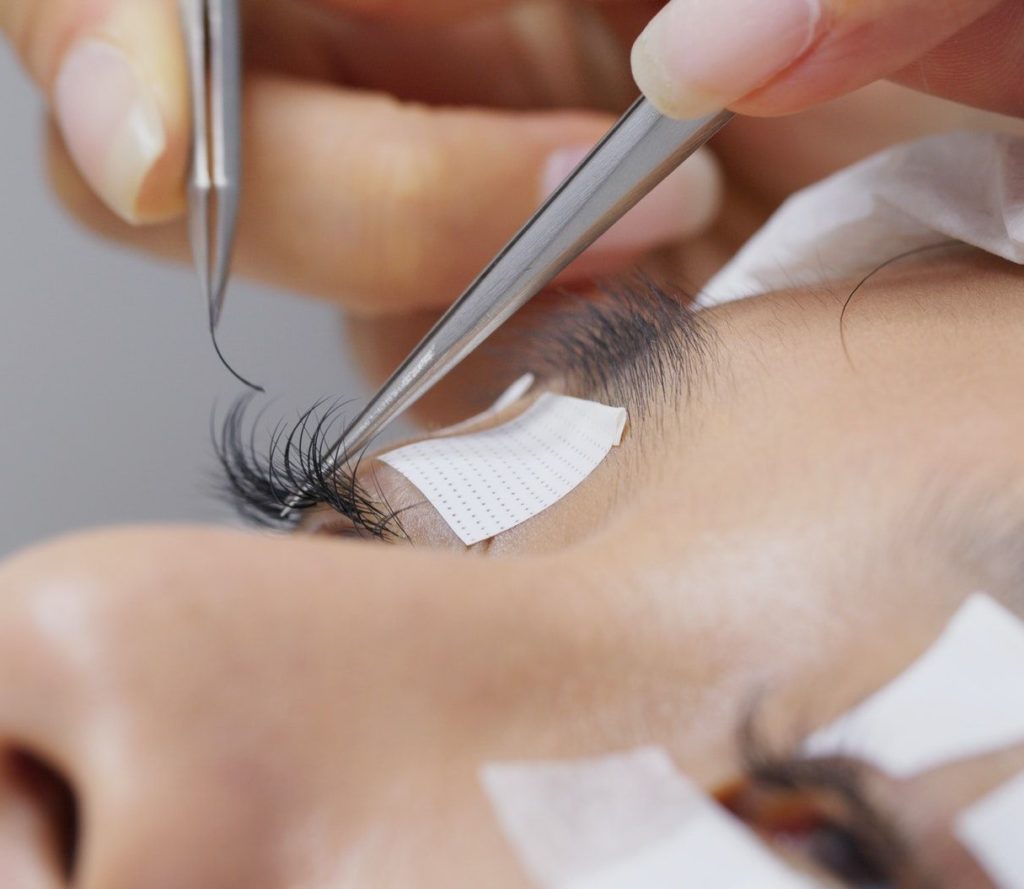 Beautician and young woman in a beauty salon with eye lash extension